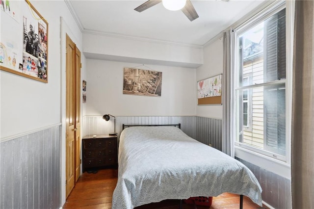 bedroom featuring ornamental molding, wood walls, ceiling fan, and dark wood-type flooring