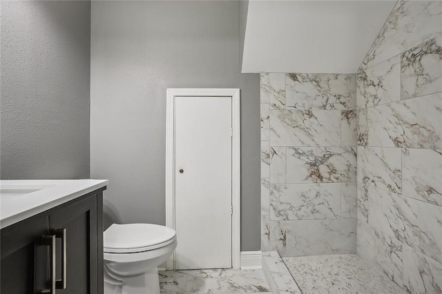 bathroom with vaulted ceiling, toilet, a tile shower, and vanity