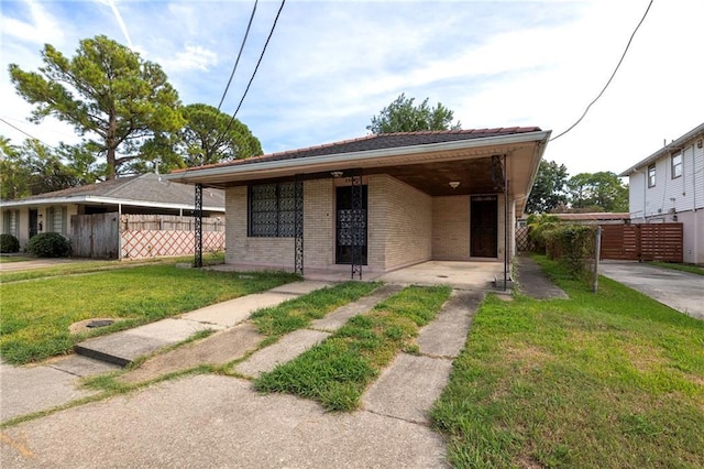 3306 Trafalgar St, New Orleans, LA 70112 - view of front of house with a front yard, an attached carport, brick siding, and fence
