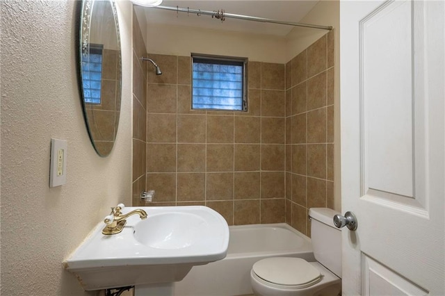 full bathroom with toilet, tiled shower / bath combo, and sink