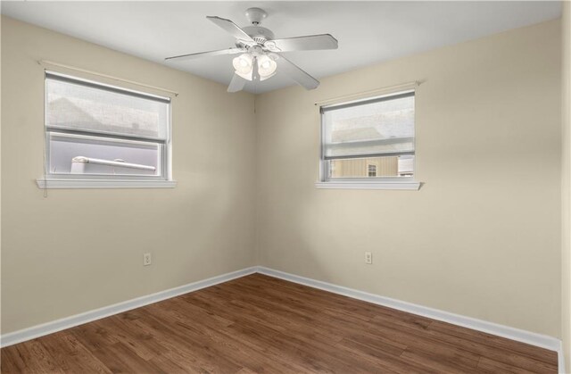 spare room with baseboards, wood finished floors, and a ceiling fan