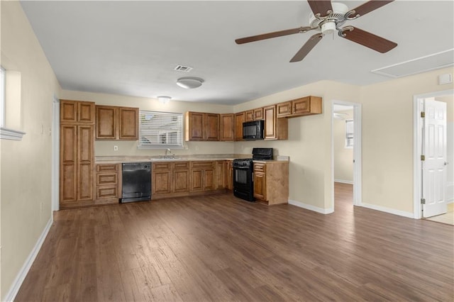 kitchen with light countertops, visible vents, a sink, dark wood-style floors, and black appliances