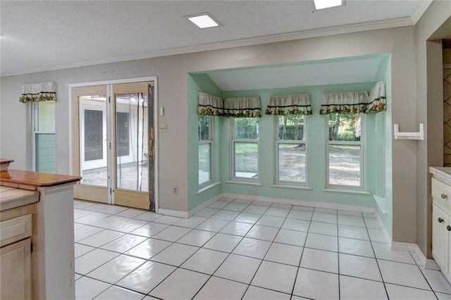 doorway with a wealth of natural light, crown molding, vaulted ceiling, and light tile patterned floors