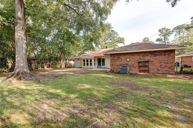 rear view of property with central AC unit and a yard