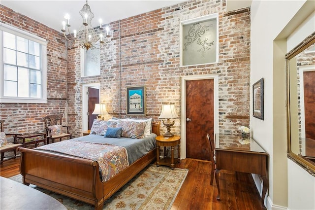 bedroom with brick wall, wood-type flooring, and a chandelier