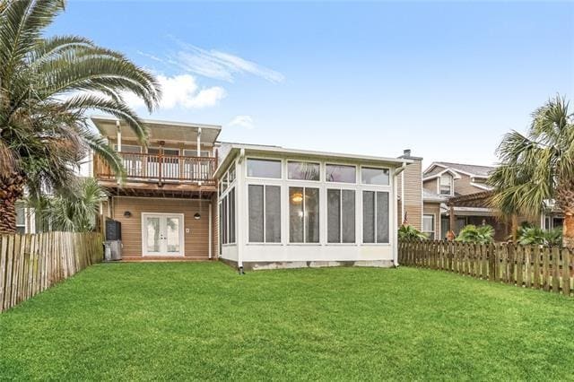 rear view of house with a balcony, a sunroom, french doors, and a yard