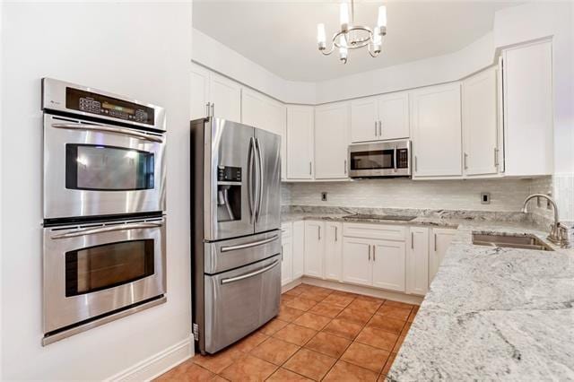 kitchen with light stone counters, sink, white cabinetry, decorative backsplash, and appliances with stainless steel finishes