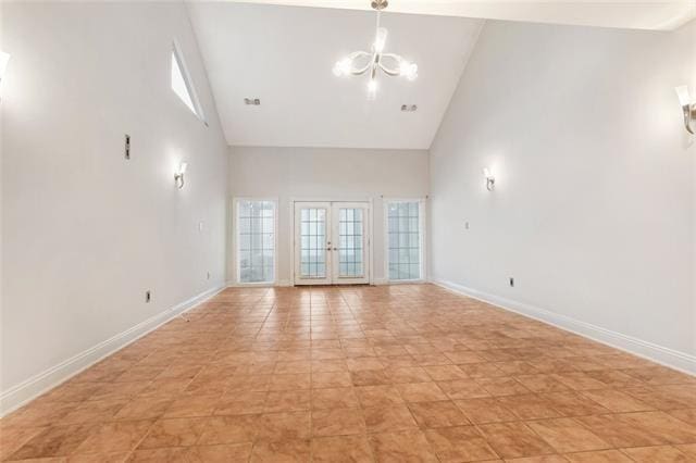 unfurnished room featuring french doors, an inviting chandelier, light tile patterned floors, and high vaulted ceiling