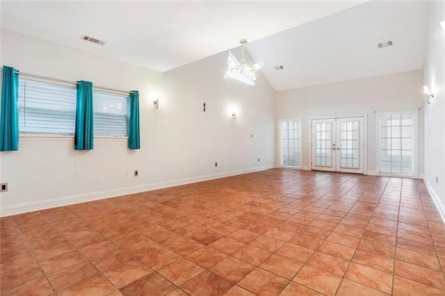 unfurnished room with an inviting chandelier, light tile patterned floors, french doors, and high vaulted ceiling