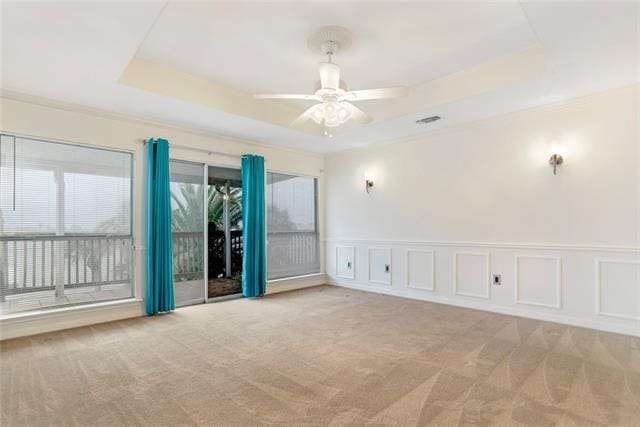 carpeted empty room with ceiling fan and a raised ceiling