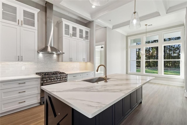 kitchen featuring white cabinets, wall chimney exhaust hood, high end range, and sink