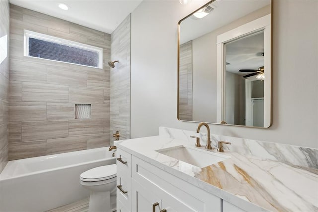 full bathroom with ceiling fan, vanity, toilet, and tiled shower / bath combo