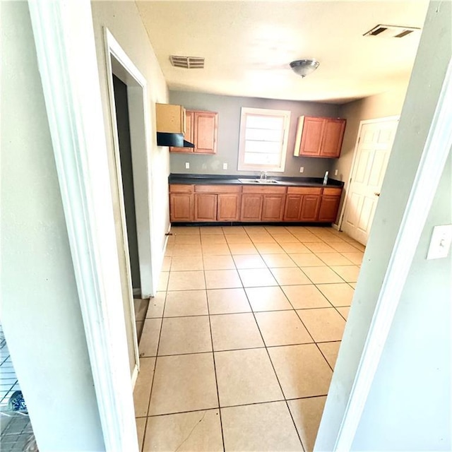 kitchen featuring light tile patterned floors, visible vents, dark countertops, and exhaust hood