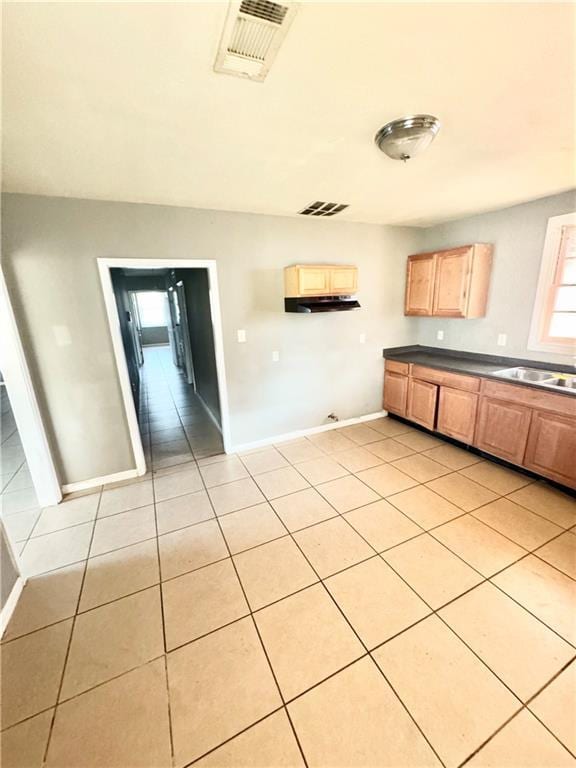 kitchen with dark countertops, baseboards, visible vents, and a sink