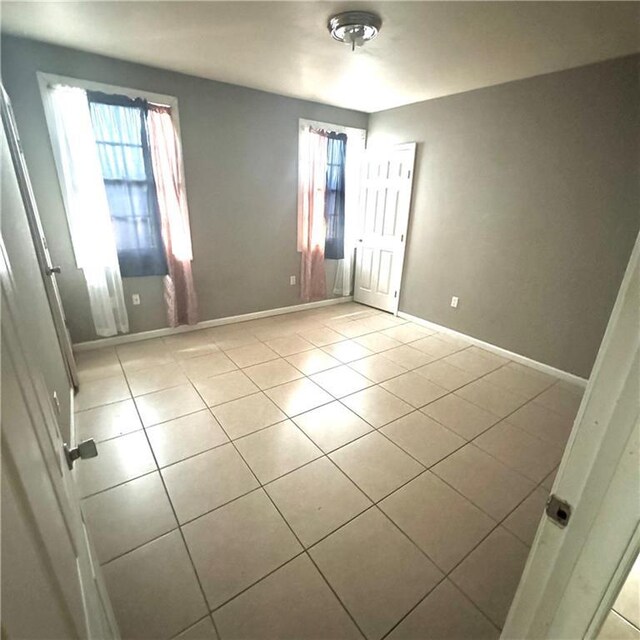 1705 Tupelo St, New Orleans, LA 70117 - unfurnished bedroom with multiple windows, light tile patterned floors, and baseboards