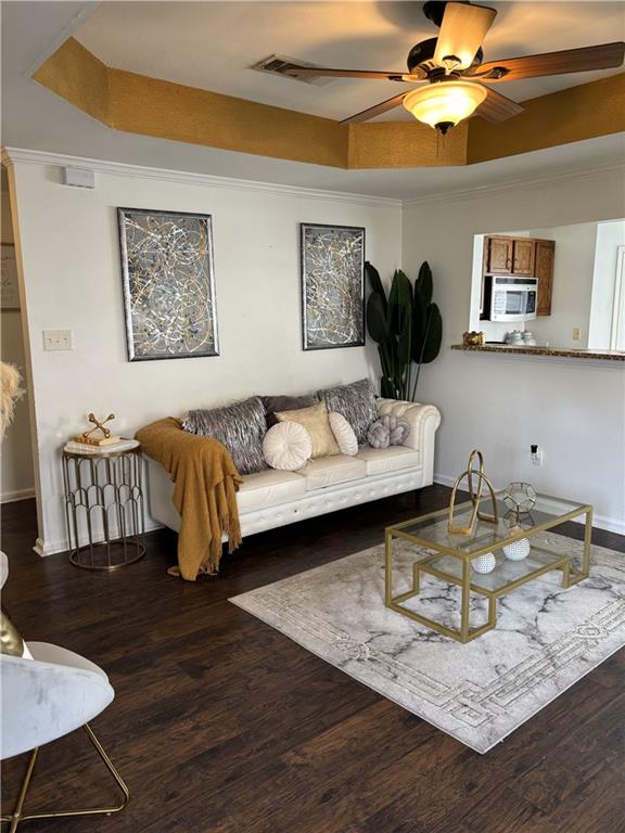 empty room featuring dark hardwood / wood-style flooring, ceiling fan with notable chandelier, a raised ceiling, and ornamental molding