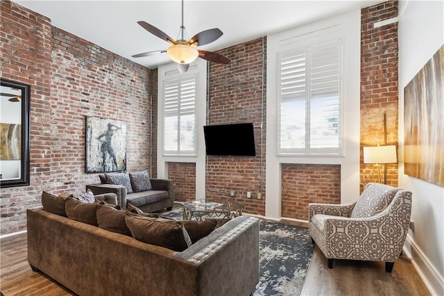 living room featuring a wealth of natural light, ceiling fan, brick wall, and hardwood / wood-style floors