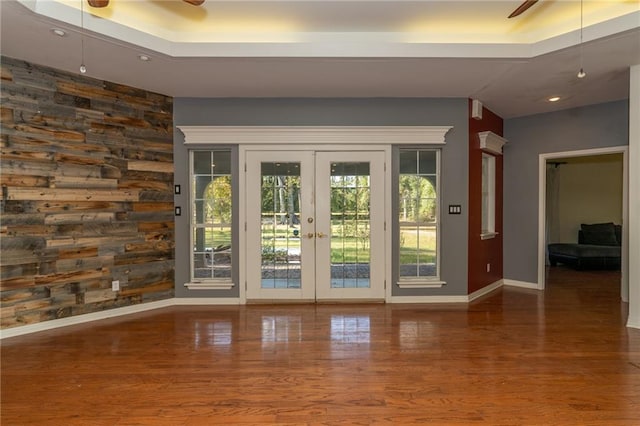 doorway to outside with french doors, ceiling fan, wood-type flooring, and a tray ceiling