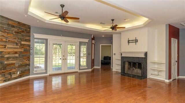 unfurnished living room with french doors, hardwood / wood-style floors, ceiling fan, and a raised ceiling