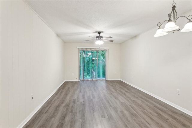 empty room with hardwood / wood-style floors, ceiling fan with notable chandelier, and ornamental molding