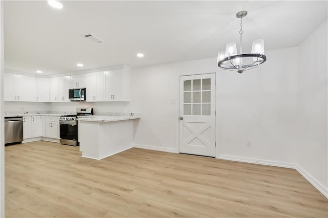 kitchen with kitchen peninsula, appliances with stainless steel finishes, white cabinetry, and light hardwood / wood-style floors