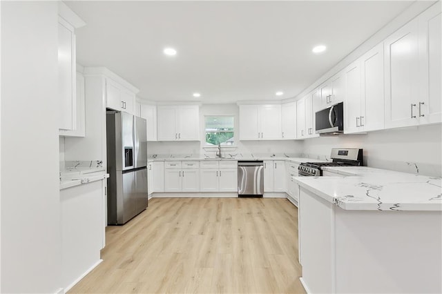 kitchen with light wood-type flooring, white cabinetry, light stone counters, and stainless steel appliances