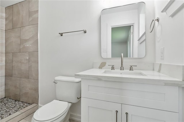 bathroom with vanity, toilet, and a tile shower