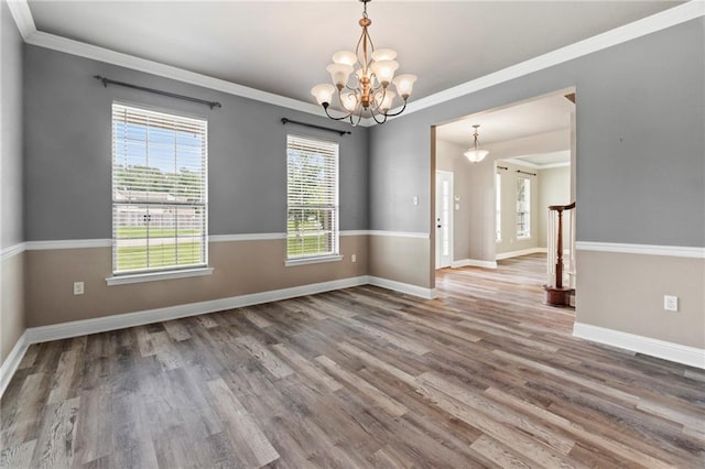 unfurnished room with a notable chandelier, wood-type flooring, and ornamental molding