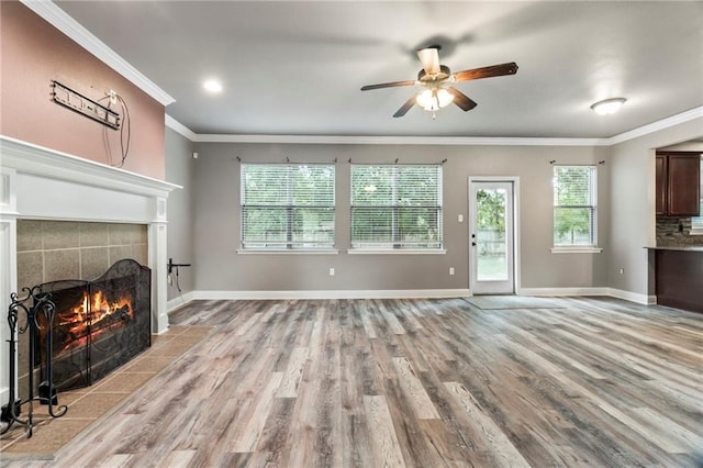 living room with a tiled fireplace, crown molding, ceiling fan, and light hardwood / wood-style floors