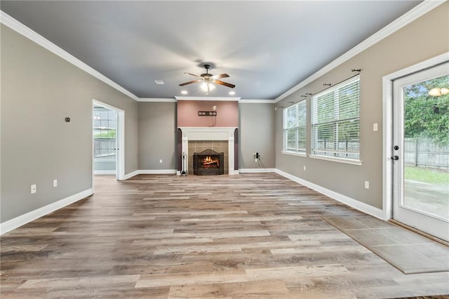 unfurnished living room featuring hardwood / wood-style floors, ceiling fan, ornamental molding, and a tiled fireplace