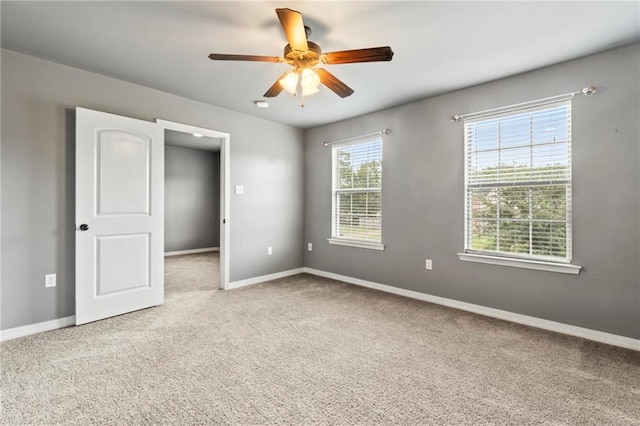 carpeted spare room featuring plenty of natural light and ceiling fan