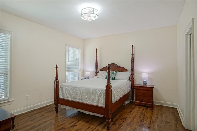 bedroom with multiple windows and dark hardwood / wood-style floors