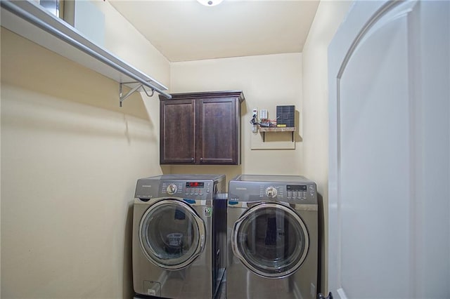 clothes washing area with washer and dryer and cabinets