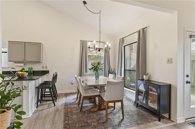 dining room featuring vaulted ceiling, wood-type flooring, and a chandelier