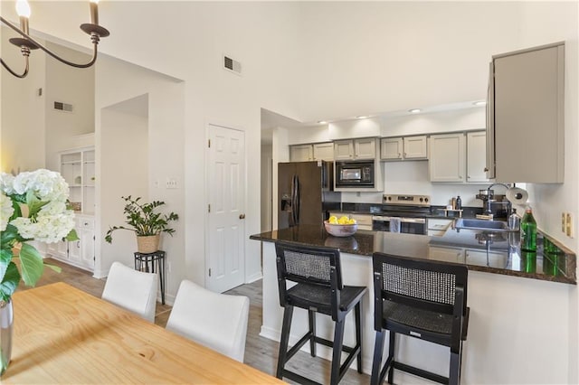 kitchen with black appliances, a kitchen bar, sink, gray cabinets, and hardwood / wood-style flooring