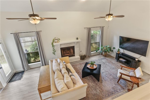 living room featuring high vaulted ceiling, ceiling fan, wood-type flooring, and a fireplace