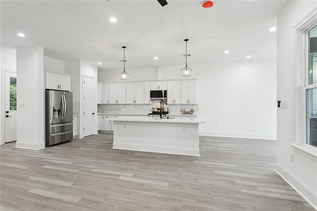 kitchen with appliances with stainless steel finishes, white cabinetry, and light hardwood / wood-style floors