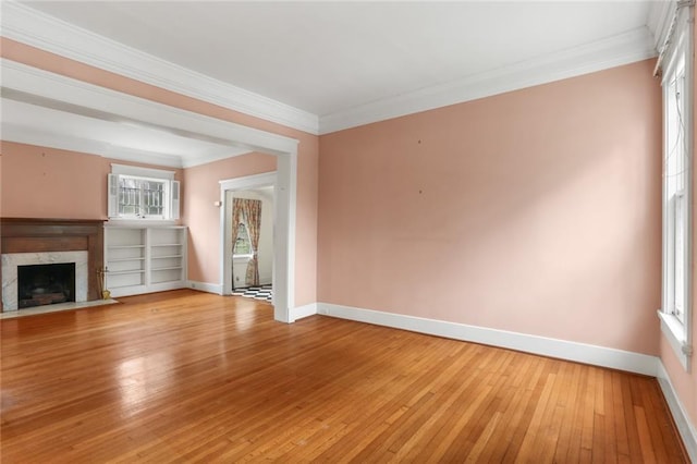 unfurnished living room featuring a high end fireplace, light wood-type flooring, and a wealth of natural light