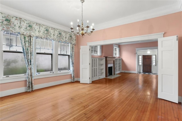 unfurnished living room featuring ornamental molding, light hardwood / wood-style flooring, and an inviting chandelier