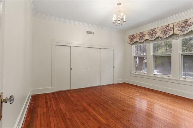 unfurnished bedroom featuring ornamental molding, light hardwood / wood-style flooring, an inviting chandelier, and a closet