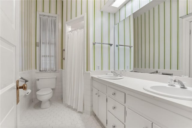 bathroom with vanity, toilet, tile walls, and tile patterned floors