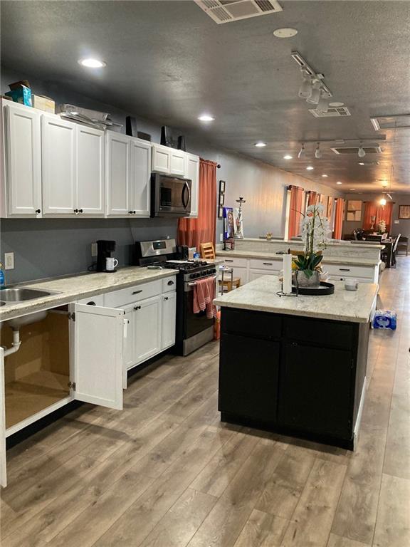 kitchen with a center island, light hardwood / wood-style flooring, stainless steel appliances, white cabinetry, and rail lighting