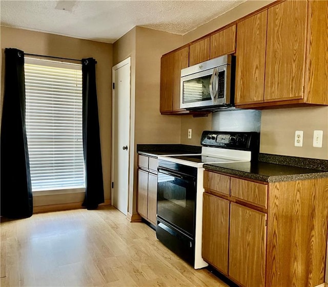 kitchen with light wood-type flooring, range with electric stovetop, and a textured ceiling