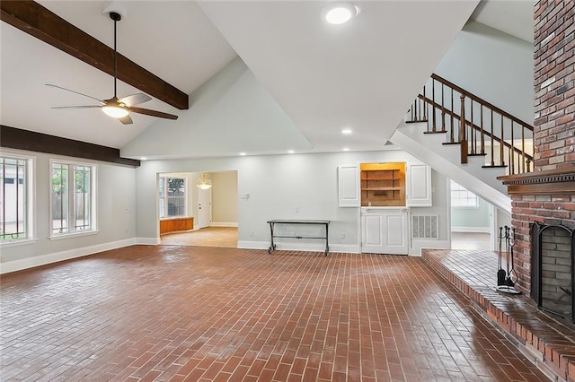 unfurnished living room featuring beamed ceiling, high vaulted ceiling, a fireplace, and ceiling fan