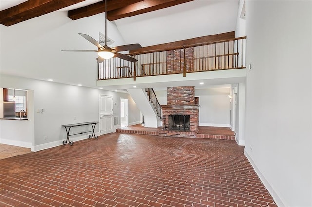 unfurnished living room featuring beam ceiling, ceiling fan, a fireplace, and high vaulted ceiling