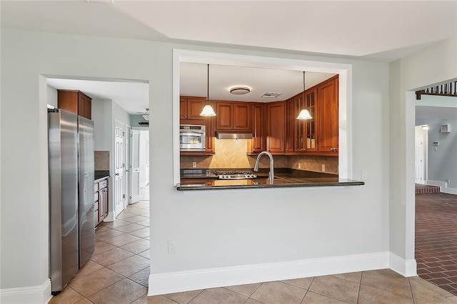 kitchen featuring kitchen peninsula, tasteful backsplash, stainless steel appliances, light tile patterned floors, and hanging light fixtures