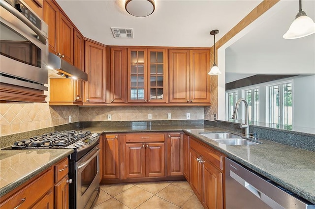 kitchen with decorative light fixtures, sink, light tile patterned floors, and stainless steel appliances