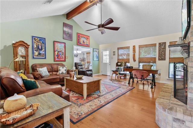 living room featuring beamed ceiling, light hardwood / wood-style flooring, ceiling fan, and a textured ceiling