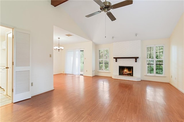 unfurnished living room featuring a fireplace, light wood-type flooring, ceiling fan with notable chandelier, and lofted ceiling