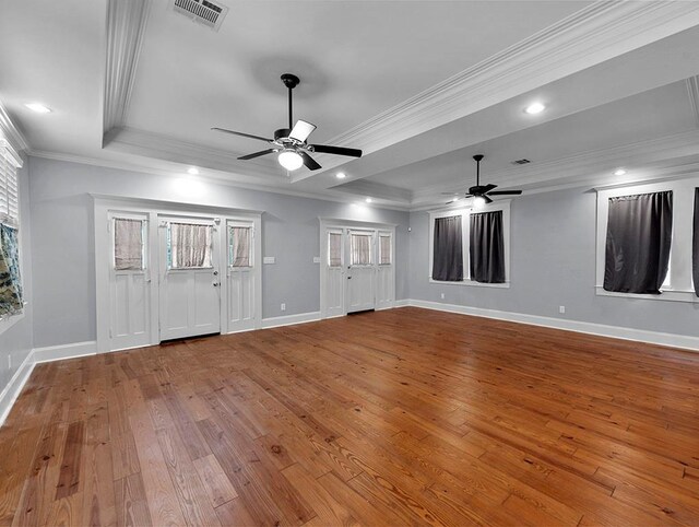 interior space with light wood-type flooring, ornamental molding, a tray ceiling, ceiling fan, and a healthy amount of sunlight